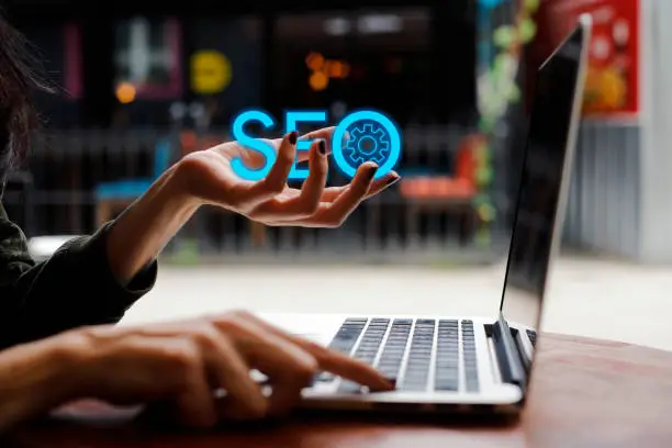 Person with laptop conjuring a floating SEO hologram, symbolizing digital marketing expertise