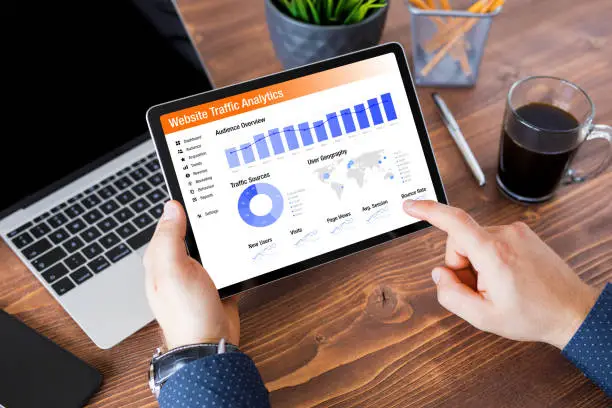 Professional analyzing website traffic data on a tablet with charts and metrics visible